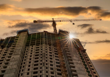 Construction crane and the building against the sunset sky